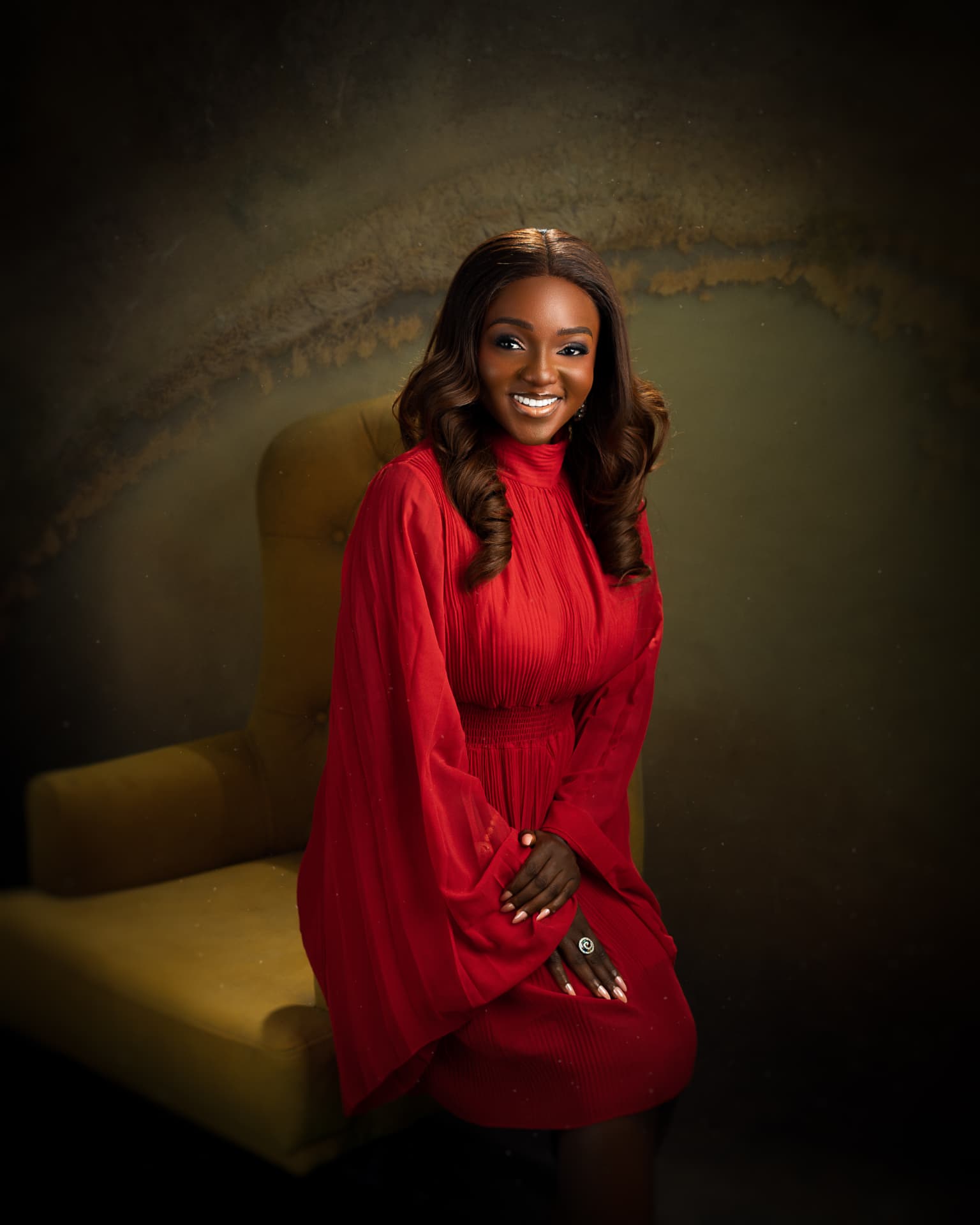 Ijidolapo Success Ijiwoye seated in a red dress, smiling warmly.